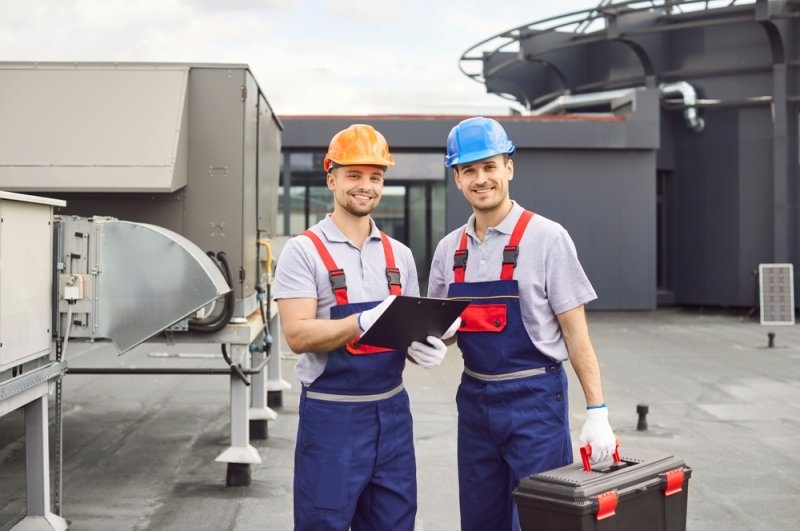 Two HVAC technicians inspecting equipment outside a commercial building.
