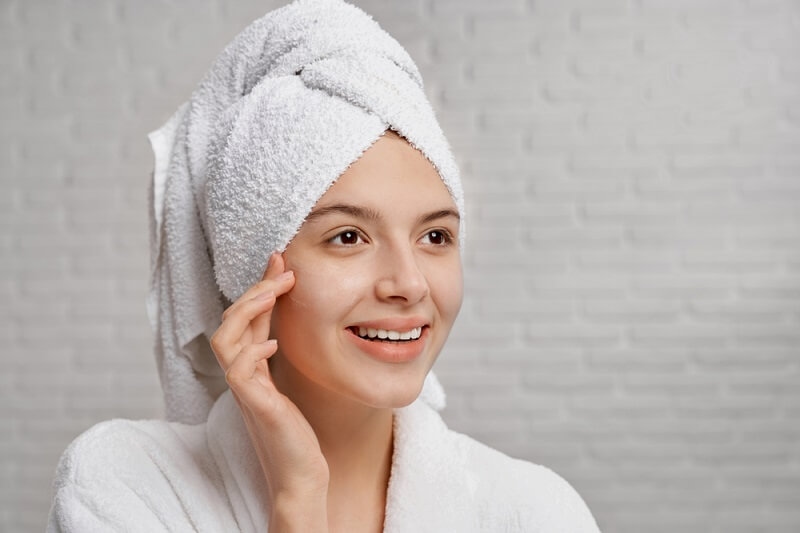 woman smiling while applying skincare products