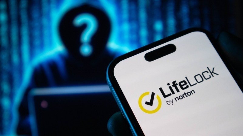 A smartphone displaying Norton LifeLock is shown against a dark background with a mysterious figure.