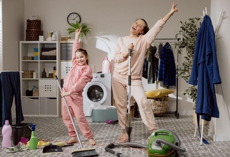 Cheerful mother and daughter spend time together while cleaning house