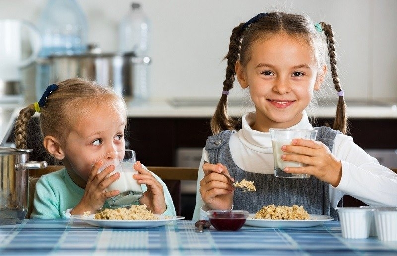 Two small smiling girls eating healthy oatmeal