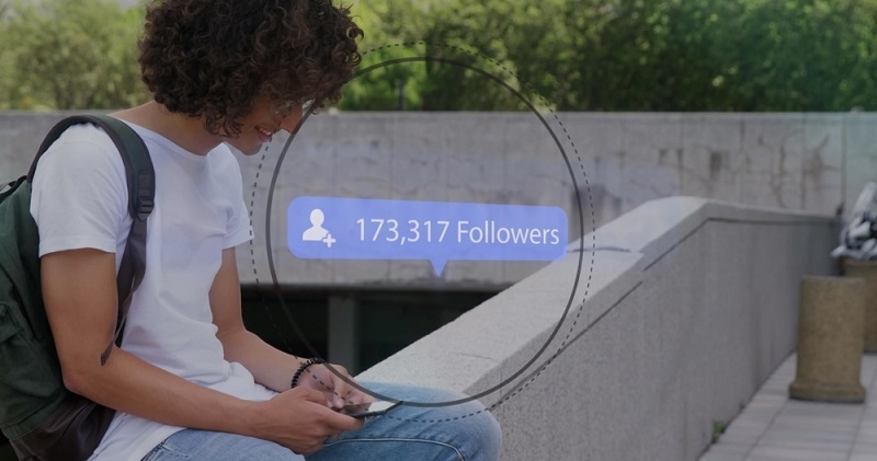 Instagram Followers text and people icon with growing numbers on blue speech bubble over man using smartphone