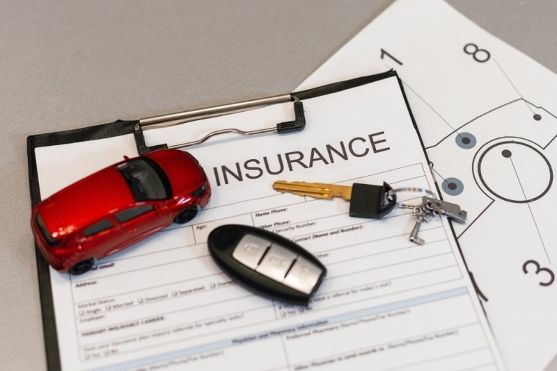 car insurance papers clipped to a board with car keys on top