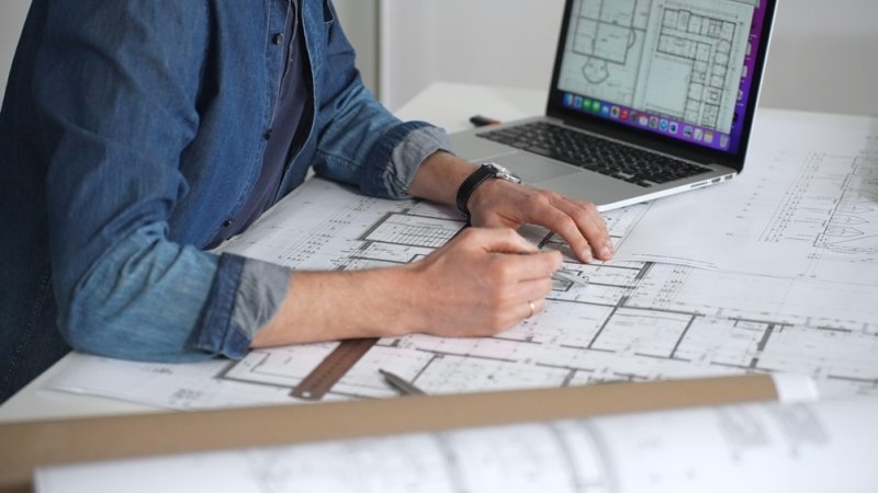 Architect drawing and measuring blueprints on a desk