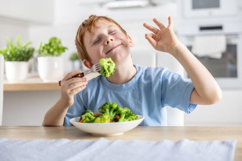 kid enjoys eating brocolli in breakfast