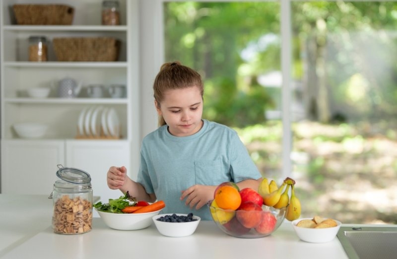 Child eat healthy food at kitchen.