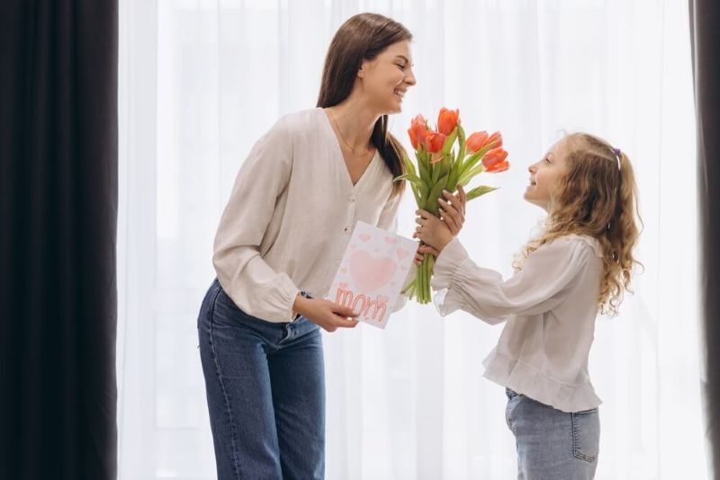 girl giving flowers to her mom
