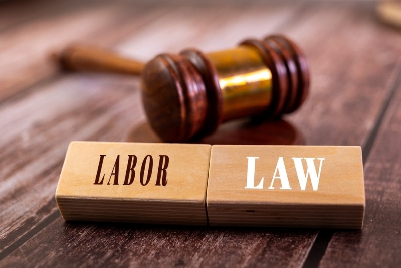 Wooden blocks labeled “LABOR” and “LAW” placed in front of a judge’s gavel.