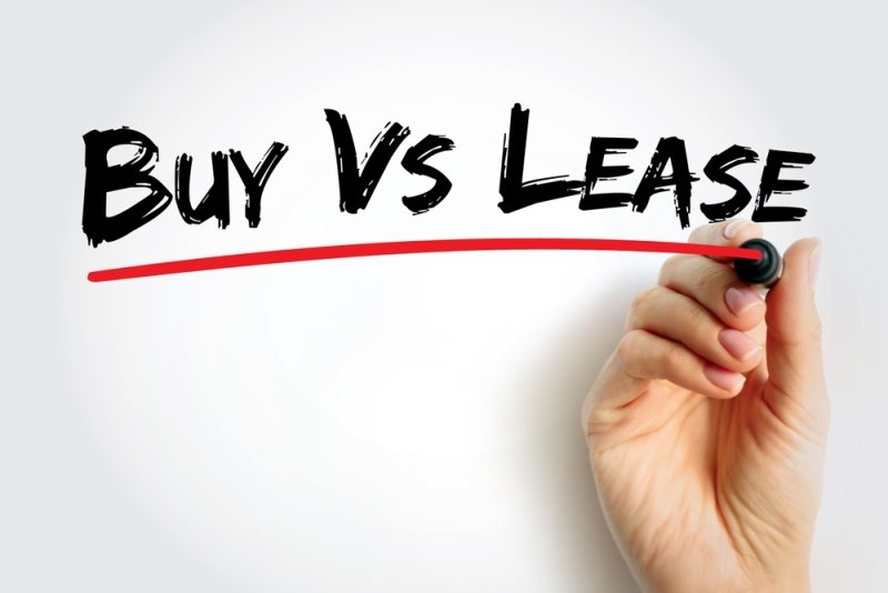 Hand writing “Buy vs Lease” in bold lettering with a red underline on a white background.
