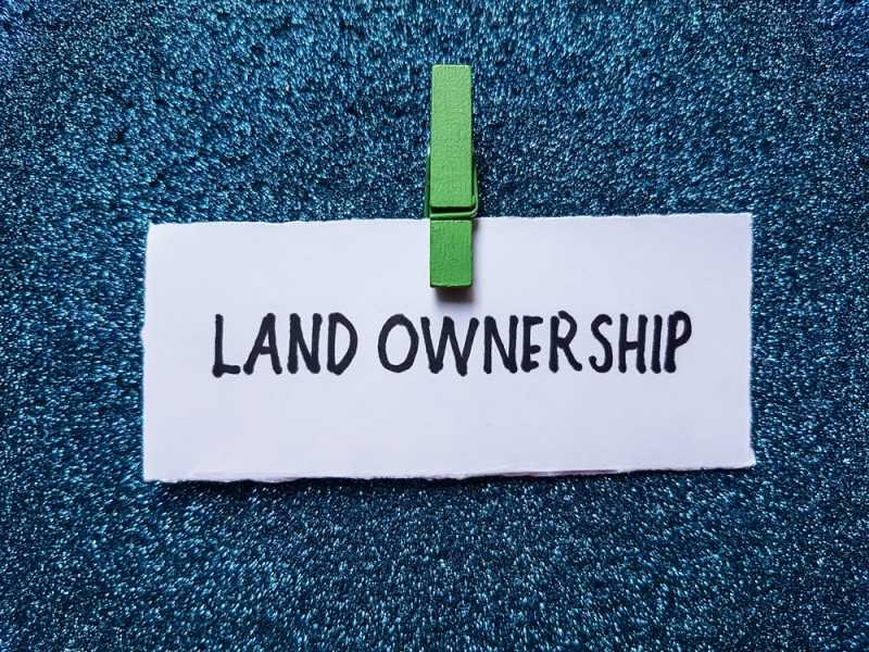 White paper labeled “Land Ownership” clipped with a green clothespin against a blue textured background.