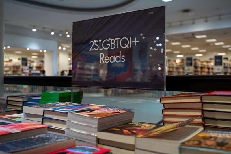 Bookstore display featuring stacks of books and a sign labeled “LGBTQ+ Reads.”