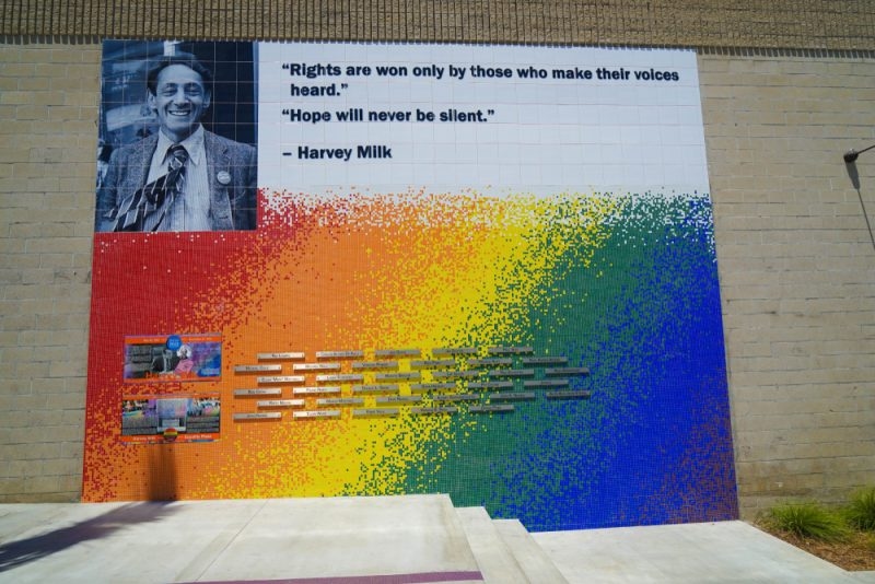 Colorful mural featuring a portrait of Harvey Milk, his quotes, and a rainbow-colored mosaic with historical names.