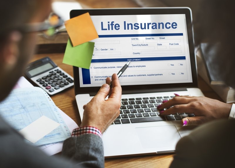 People reviewing a life insurance form on a laptop.
