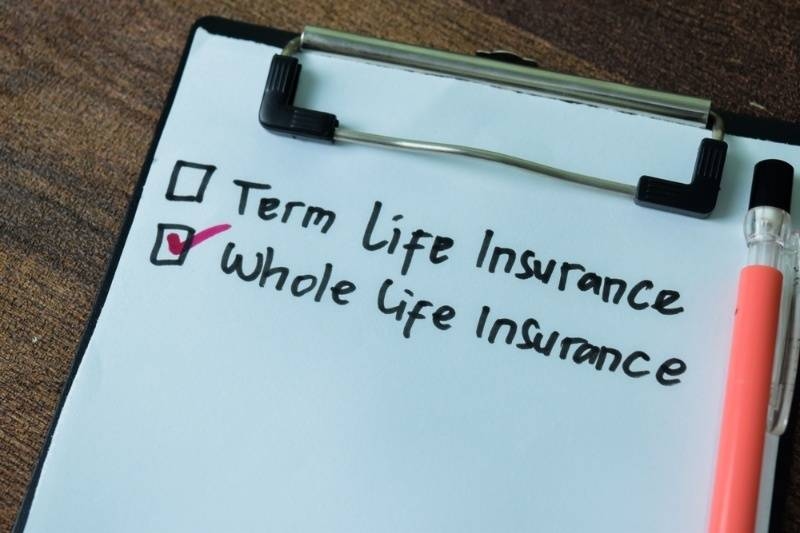 Checklist comparing term life insurance and whole life insurance on a clipboard.