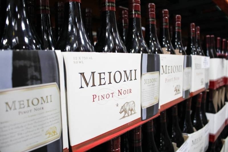 Rows of Meiomi Pinot Noir wine bottles displayed on retail shelves in a wine store.