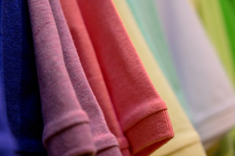 collection of cotton t-shirts in various colors hangs on a rack