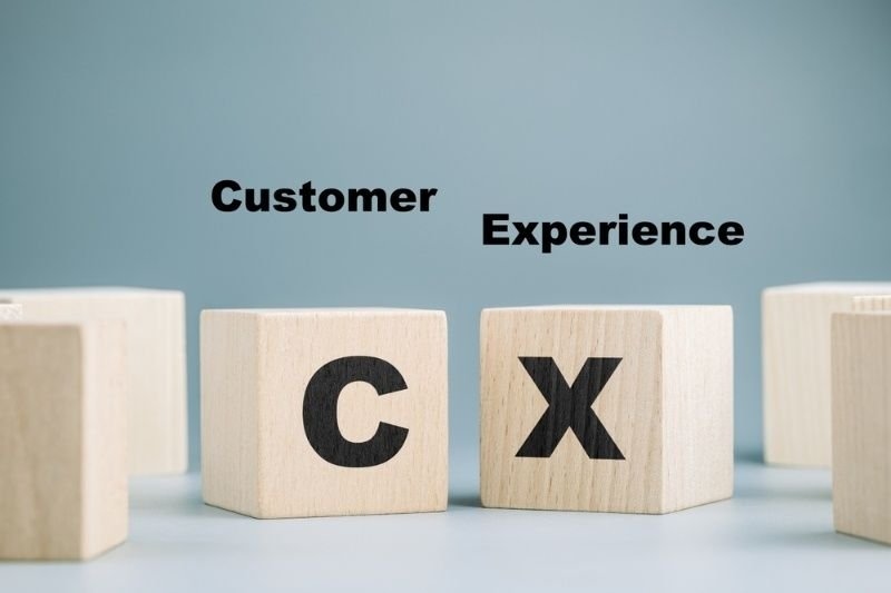 Wooden blocks spell “CX” with the words “Customer Experience” above them.