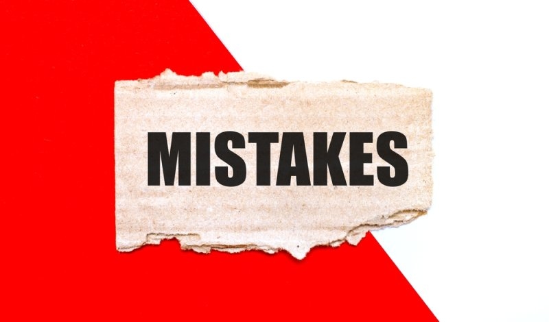 Torn paper labeled “MISTAKES” placed against a bold red and white background.
