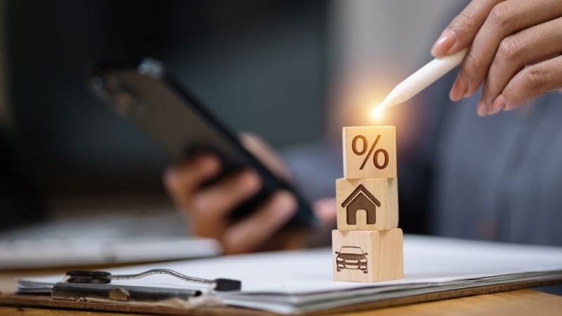 Man using smartphone and stylus next to loan documents 