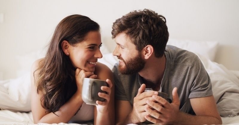 A smiling couple sitting together and sharing a relaxed conversation over coffee.
