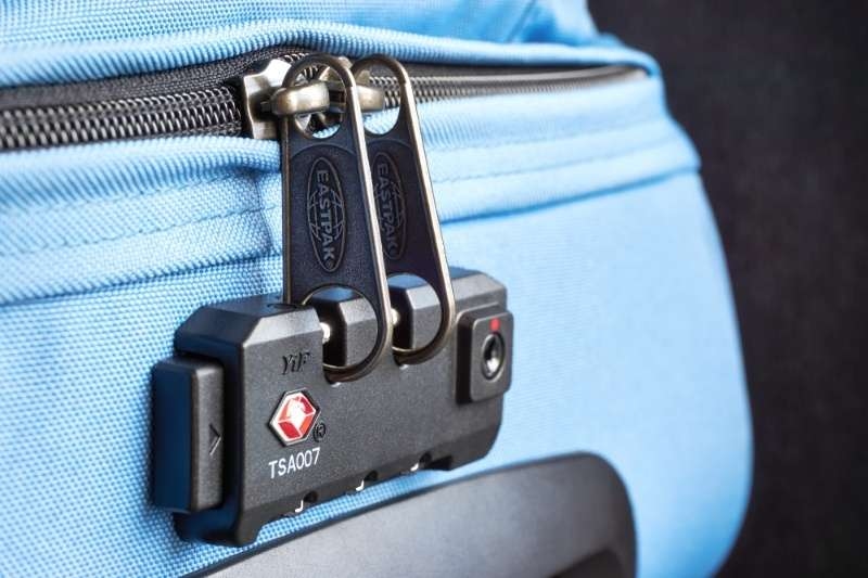 Close-up of a blue suitcase secured with a TSA-approved combination luggage lock.