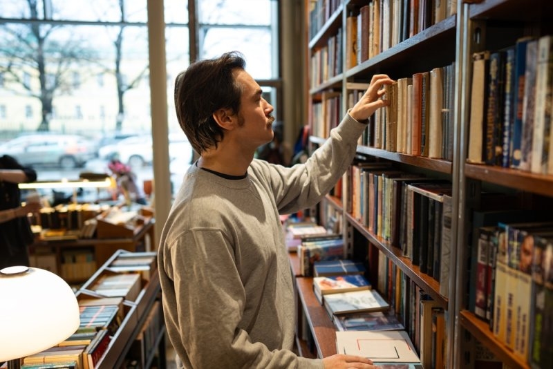 man searching for books in library