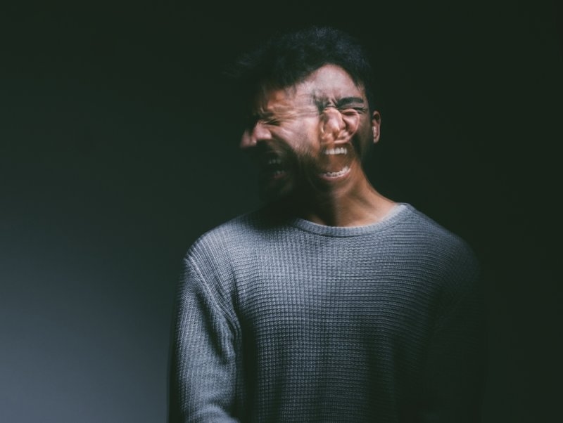 Man in a dark setting expressing intense distress or emotional pain.