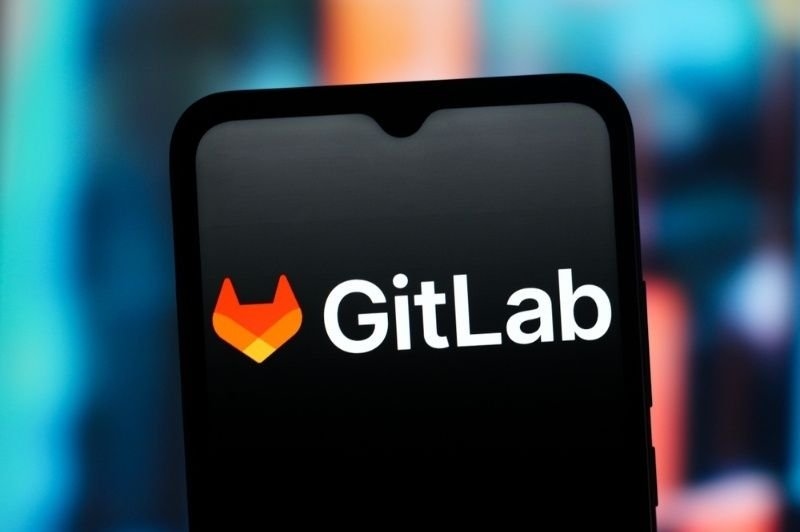 A close-up of a smartphone displaying the GitLab logo and name against a dark, colorful background.