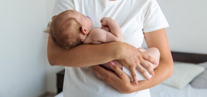 Mother gently holding and comforting her newborn baby at home.