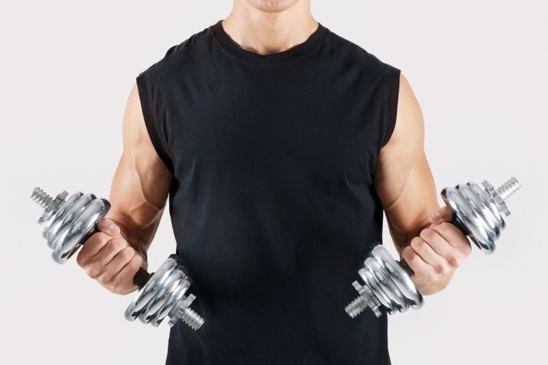 Man performing bicep curls with dumbbells, showcasing arm strength and muscle workout.