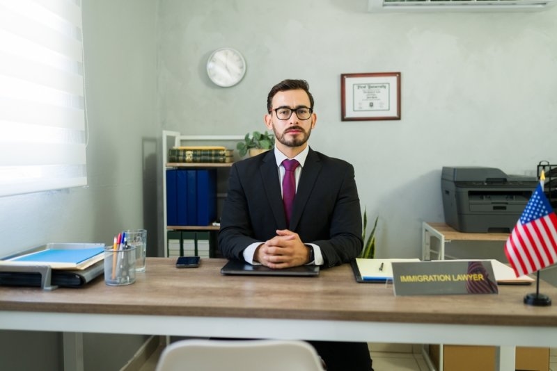 Serious immigration lawyer sitting at desk in office.