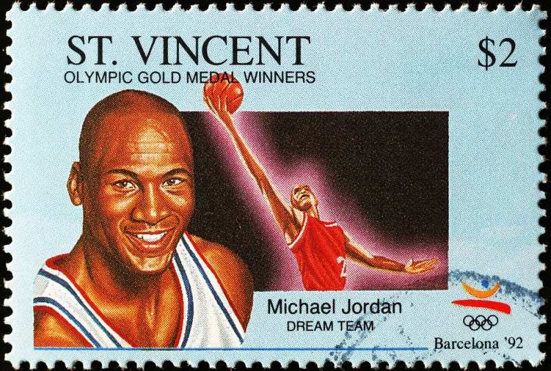 Commemorative St. Vincent postage stamp featuring Michael Jordan in a basketball jersey and an action illustration of him playing for the Dream Team at the Barcelona 1992 Olympics.