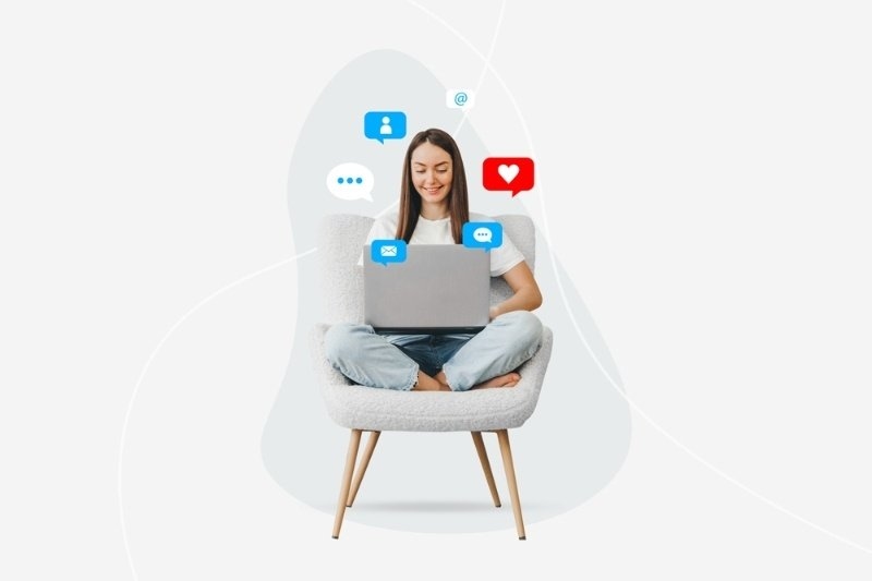 A woman sits in a chair using a laptop, surrounded by floating social media icons for messages, likes, profiles, and email, representing online engagement and content creation.