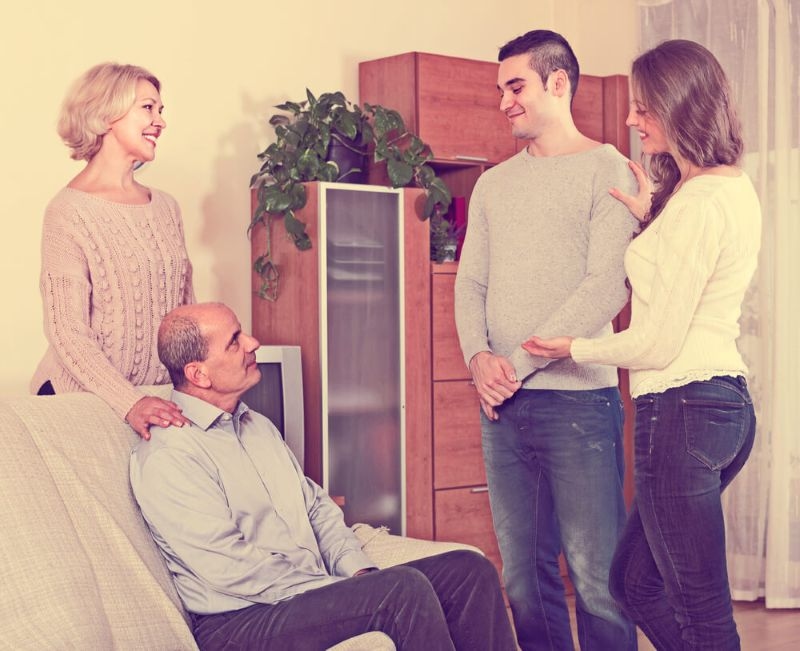 Happy adult daughter introducing her boyfriend to her parents indoor