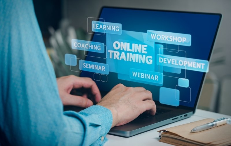A person typing on a laptop with "online training" text and various related keywords.