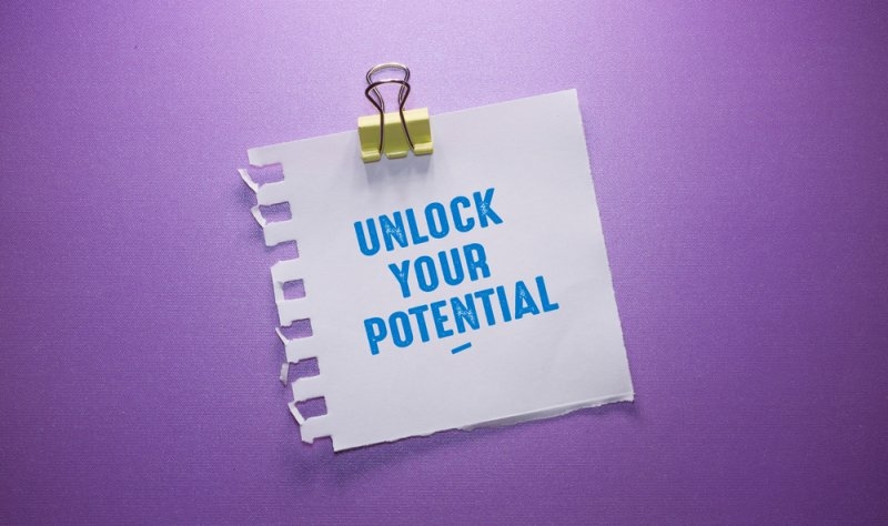 A note reading “Unlock Your Potential” clipped against a purple background, symbolizing personal or business growth.