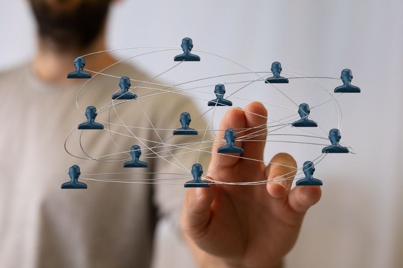 Person interacting with a digital social network visualization showing connected user icons.