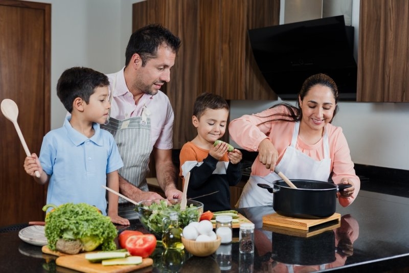 Parents and children preparing food together in the kitchen