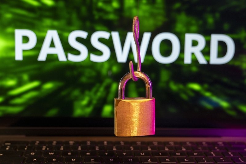 Padlock hanging in front of a laptop with the word “PASSWORD” displayed on the screen, representing digital security.