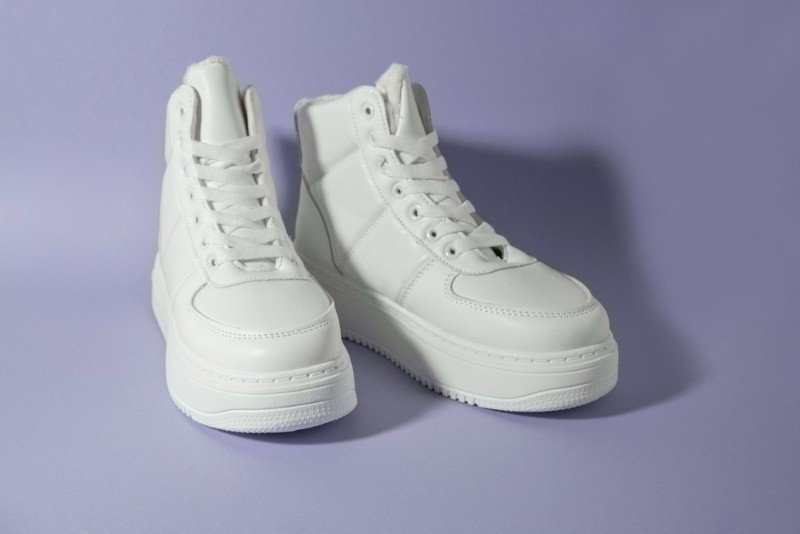 White winter platform sneakers on pastel purple background.