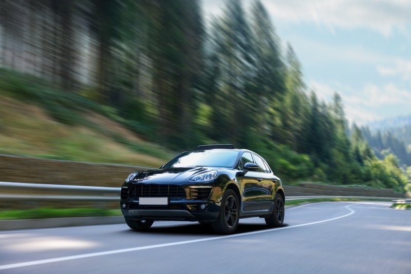 Black luxury SUV driving along a scenic mountain road.
