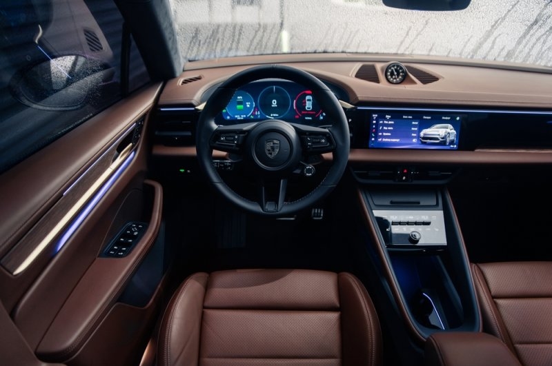 Close-up view of the Taycan’s modern interior, featuring a digital instrument cluster, touchscreen displays, and brown leather seats.