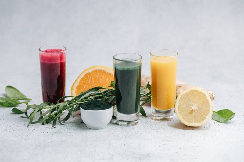 Home made detox drinks from dissolved powder in composition with fruit, ginger root and tarragon. On the table.