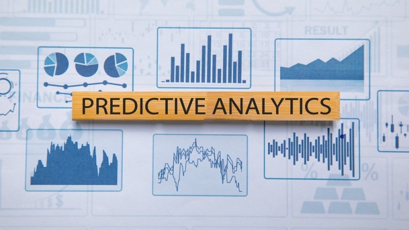 Text Predictive Analytics printed on a wooden block on top of bar graphs and charts