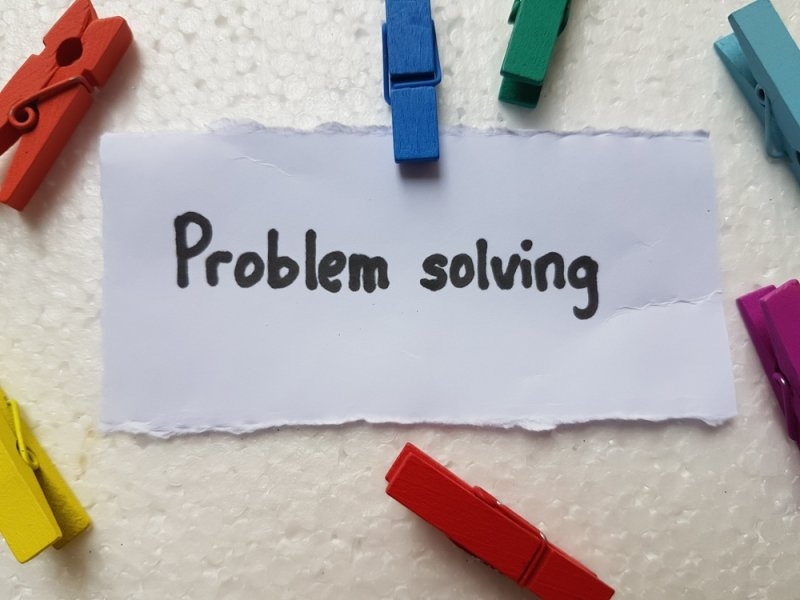 Handwritten “Problem solving” message on paper surrounded by colorful clothespins.