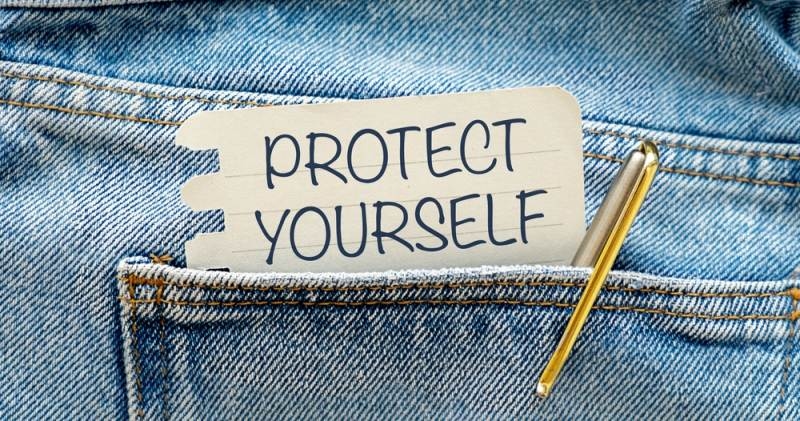 "Protect Yourself" text message on white paper in pocket with pen on blue jeans background
