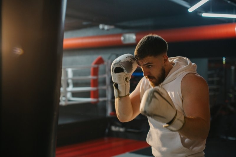 Boxer practicing punches on a heavy punching bag in a gym.