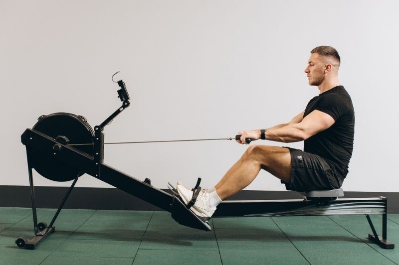 Man exercising on a rowing machine in a gym, focusing on cardio workout.