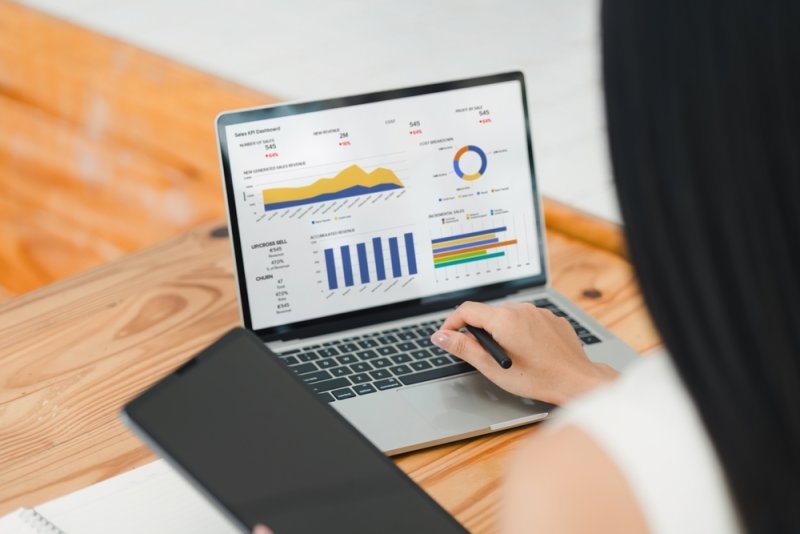 Person using a laptop displaying sales dashboards with revenue charts, performance metrics, and analytics graphs.