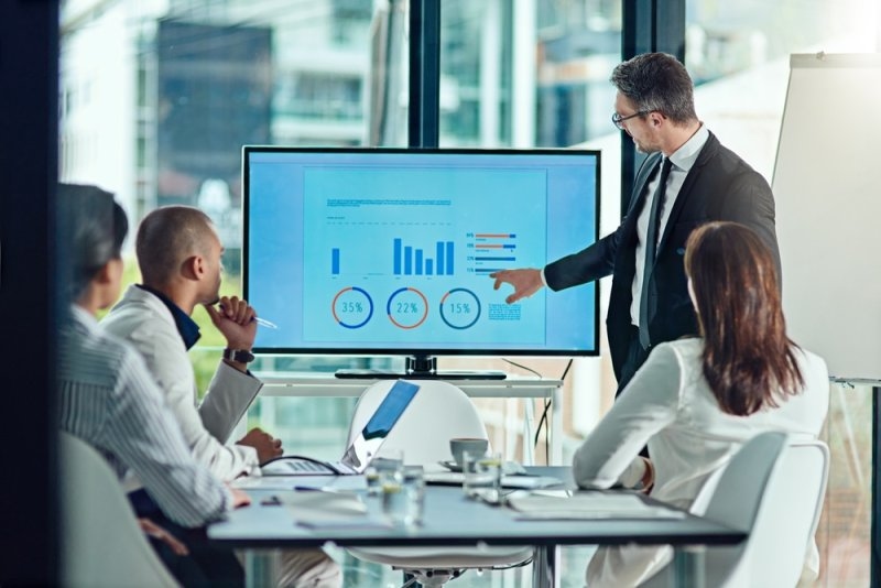 Business professional presenting sales data and performance charts to colleagues during a meeting.